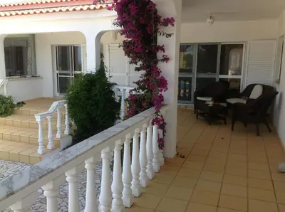 a house with a white railing and purple flowers at Casa Borboleta Gepflegte Villa mit Meerblick, großem Garten und Pool, Traumlage in Aljezur
