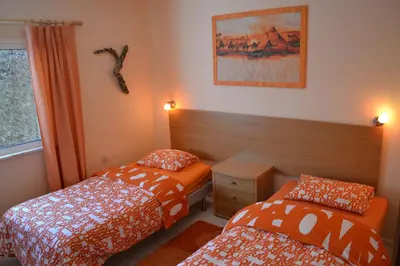 a bedroom with two beds and a table and a window at Casa Borboleta Gepflegte Villa mit Meerblick, großem Garten und Pool, Traumlage in Aljezur