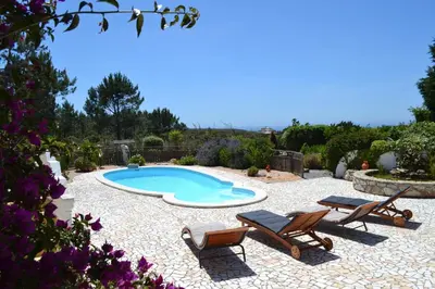a swimming pool in a yard with two chairs and a table at Casa Borboleta Gepflegte Villa mit Meerblick, großem Garten und Pool, Traumlage in Aljezur