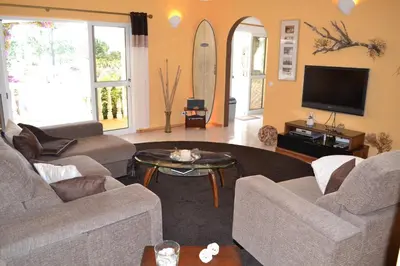 a living room with couches and a flat screen tv at Casa Borboleta Gepflegte Villa mit Meerblick, großem Garten und Pool, Traumlage in Aljezur