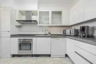 a white kitchen with white cabinets and appliances at Serenity Solace by Homie in Funchal