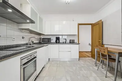 a kitchen with white cabinets and a wooden table at Serenity Solace by Homie in Funchal