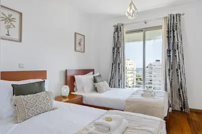 a bedroom with two beds and a large window at Serenity Solace by Homie in Funchal