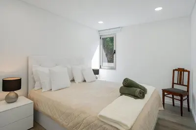 a white bedroom with a bed and a table at OurMadeira - TerraceSea Apartments in Ribeira Brava