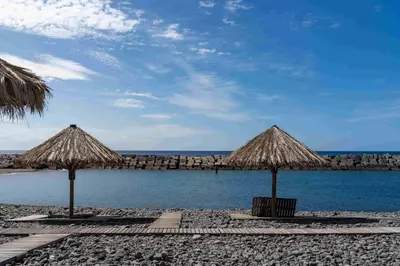 two people sitting on the side of a mountain overlooking a river at OurMadeira - TerraceSea Apartments in Ribeira Brava