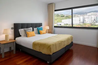 a bedroom with a large bed with a large window at Amparo II by An Island Apart in Funchal