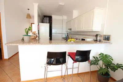 a kitchen with white cabinets and black bar stools at Musa Apartment in Madalena do Mar