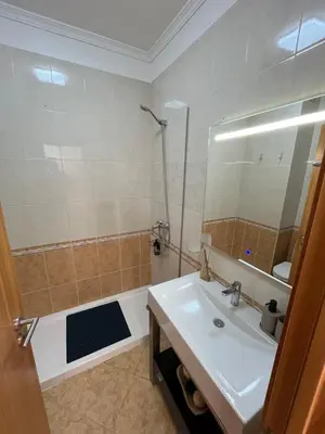 a bathroom with a sink and a shower with a mirror at Musa Apartment in Madalena do Mar