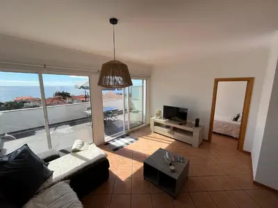 a living room with a couch and a television at Musa Apartment in Madalena do Mar