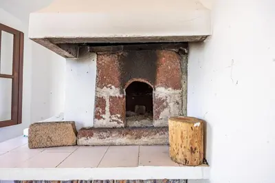 a brick oven in a white room with a wooden stump at Silva Retreat Villa in São Jorge