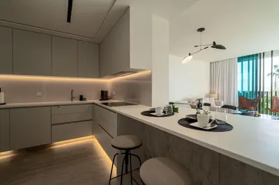 a kitchen with white cabinets and a counter with stools at Savoy Residence Monumentalis N&N by LM&AC Signature in Funchal