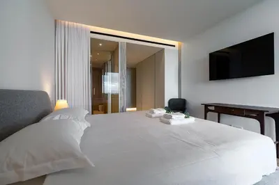 a bedroom with a large white bed and a television at Savoy Residence Monumentalis N&N by LM&AC Signature in Funchal