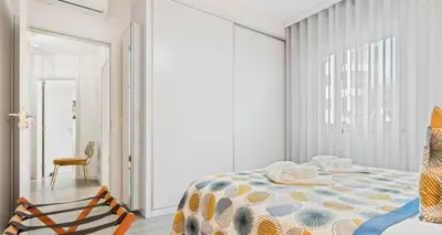 a white bedroom with a bed and a chair at Indigo Apartment By The Madeira Luxury Collection in Funchal