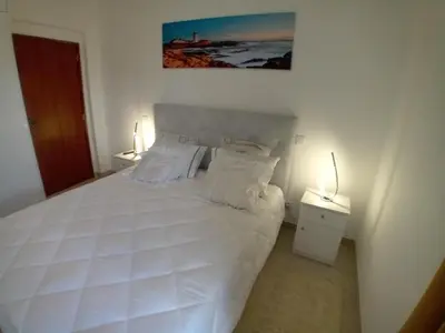 a bedroom with a large white bed with two lamps at apartamento Zarco in Machico