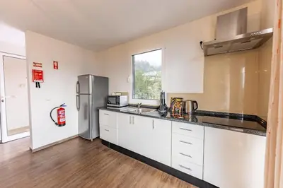 a kitchen with white cabinets and a stainless steel refrigerator at Recanto do Caminheiro by YOUR KEY in Santana