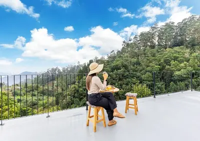 a woman sitting on a chair on a balcony looking at the mountains at Recanto do Caminheiro by YOUR KEY in Santana