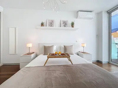 a white bedroom with a large bed with two lamps at Acanto Loft by Atlantic Holiday in Funchal
