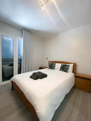 a bedroom with a large white bed and a window at Village Square Coastal Apartment 1D in Machico
