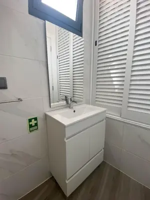 a white bathroom with a sink and a window at Village Square Coastal Apartment 1D in Machico
