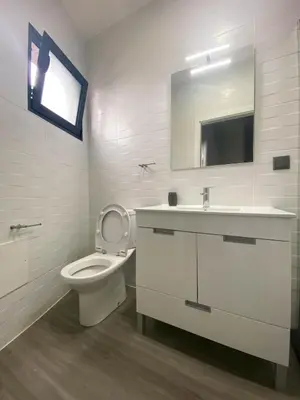 a bathroom with a toilet and a sink and a mirror at Village Square Coastal Apartment 1D in Machico