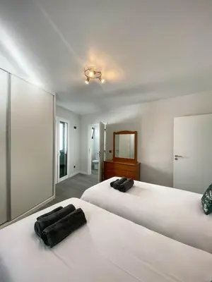 a bedroom with two white beds and a mirror at Village Square Coastal Apartment 1D in Machico