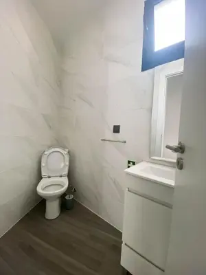 a white bathroom with a toilet and a sink at Village Square Coastal Apartment 1D in Machico