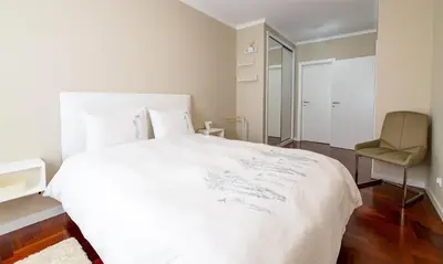 a white bedroom with a bed and a chair at Garajau Terrace Atlântico in Garajau