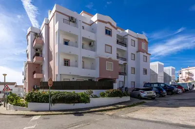 a tall white building with cars parked in a parking lot at Luz Heaven - Top floor Seaview Apartment in Luz