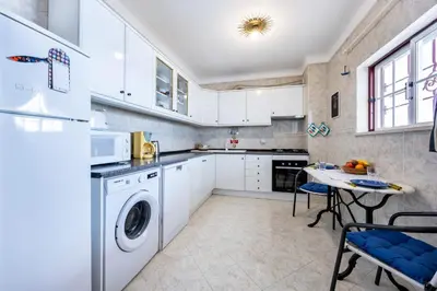 a kitchen with white cabinets and a table with chairs at Luz Heaven - Top floor Seaview Apartment in Luz