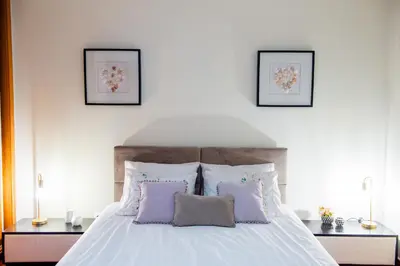 a bedroom with a white bed with purple pillows at Bugio Guesthouse in Santa Cruz