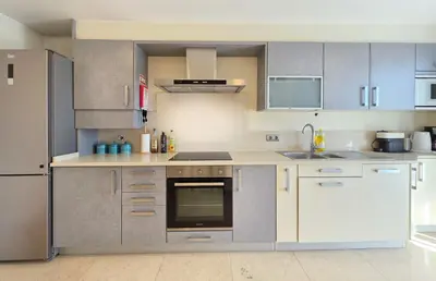 a kitchen with white appliances and gray cabinets at Fórum Madeira Residence in Funchal