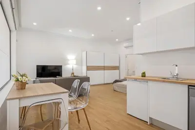 a kitchen and living room with white cabinets at Casa Isaurinha by ALMA Holiday Rentals in Caniço