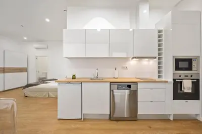 a kitchen with white cabinets and a bed in the background at Casa Isaurinha by ALMA Holiday Rentals in Caniço