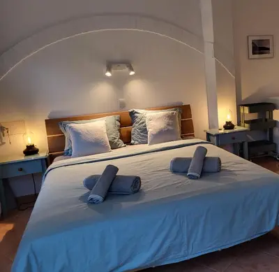 a large white bed with two blue pillows on it at Casa Monki in Raposeira