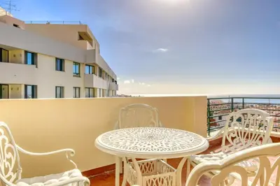 a balcony with a table and chairs and a building at Funchal Panoramic View, a Home in Madeira in Funchal
