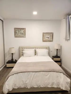 a white bedroom with a large bed with two lamps at Santa Beatriz Apartment in Machico
