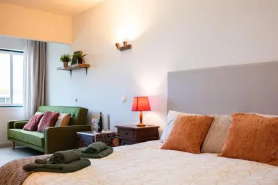 a bedroom with a bed and a couch and a chair at Seaview Ensuite rooms in Sagres centre - Casa Maluka in Sagres