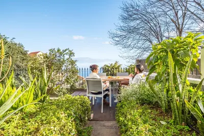 two women sitting at a table in a garden at Villa Monte in Funchal