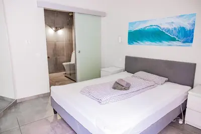 a white bedroom with a bed and a bathroom at Living Lodge Portugal in Aljezur