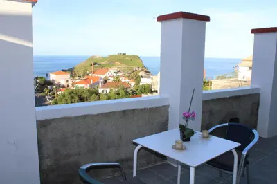 a table and chairs on a balcony with a view of the ocean at Leais ao Pico in Porto da Cruz