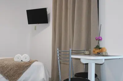 a room with a table and a bed and a tv at Leais ao Pico in Porto da Cruz