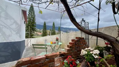 a patio with a table and a brick wall at Rosalita s View in Funchal