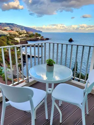 a table and chairs on a deck with a view of the ocean at Apartamento Vista Mar in Funchal