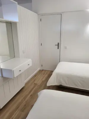 a white bedroom with a bed and a mirror at Apartamento Vista Mar in Funchal