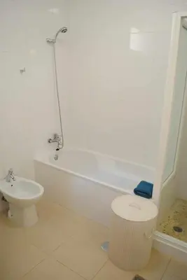 a white bathroom with a toilet and a bath tub at GuestReady - Vila Rosa - Renovated Seaviews House in Funchal