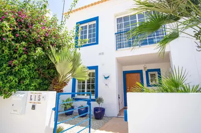 a white house with blue windows and plants at Baleias Guesthouse - 3 Bedroom Townhouse with private pool & sea view in Luz