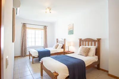 a bedroom with two beds and a window at Baleias Guesthouse - 3 Bedroom Townhouse with private pool & sea view in Luz