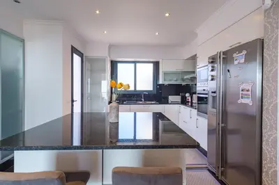 a kitchen with white cabinets and a stainless steel refrigerator at GuestReady - Private Terrace Stay in Funchal