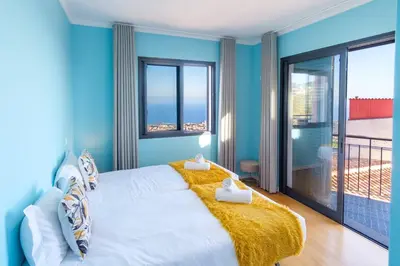 a blue bedroom with a large bed and a balcony at GuestReady - Private Terrace Stay in Funchal