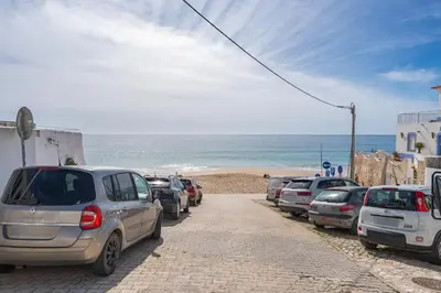 a row of cars parked on a street next to the beach at Studio Sardinha-1 min walk to beach in Burgau